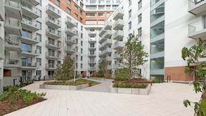 A modern multi-story residential building with balconies, a central courtyard with planters, and a brick facade. - RentPlanet - Apartamenty Żurawie (Gdansk)