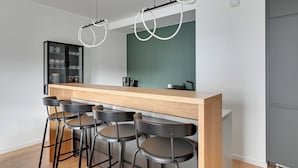A modern kitchen with a wooden bar and black stools. - RentPlanet - Apartamenty Żurawie (Gdansk)