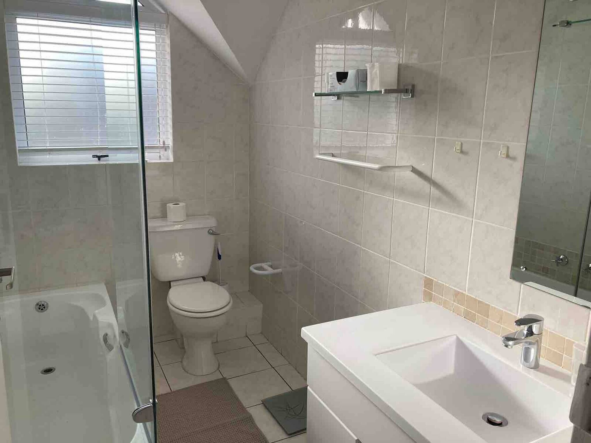 A bathroom with a toilet, a shower, and a sink.
