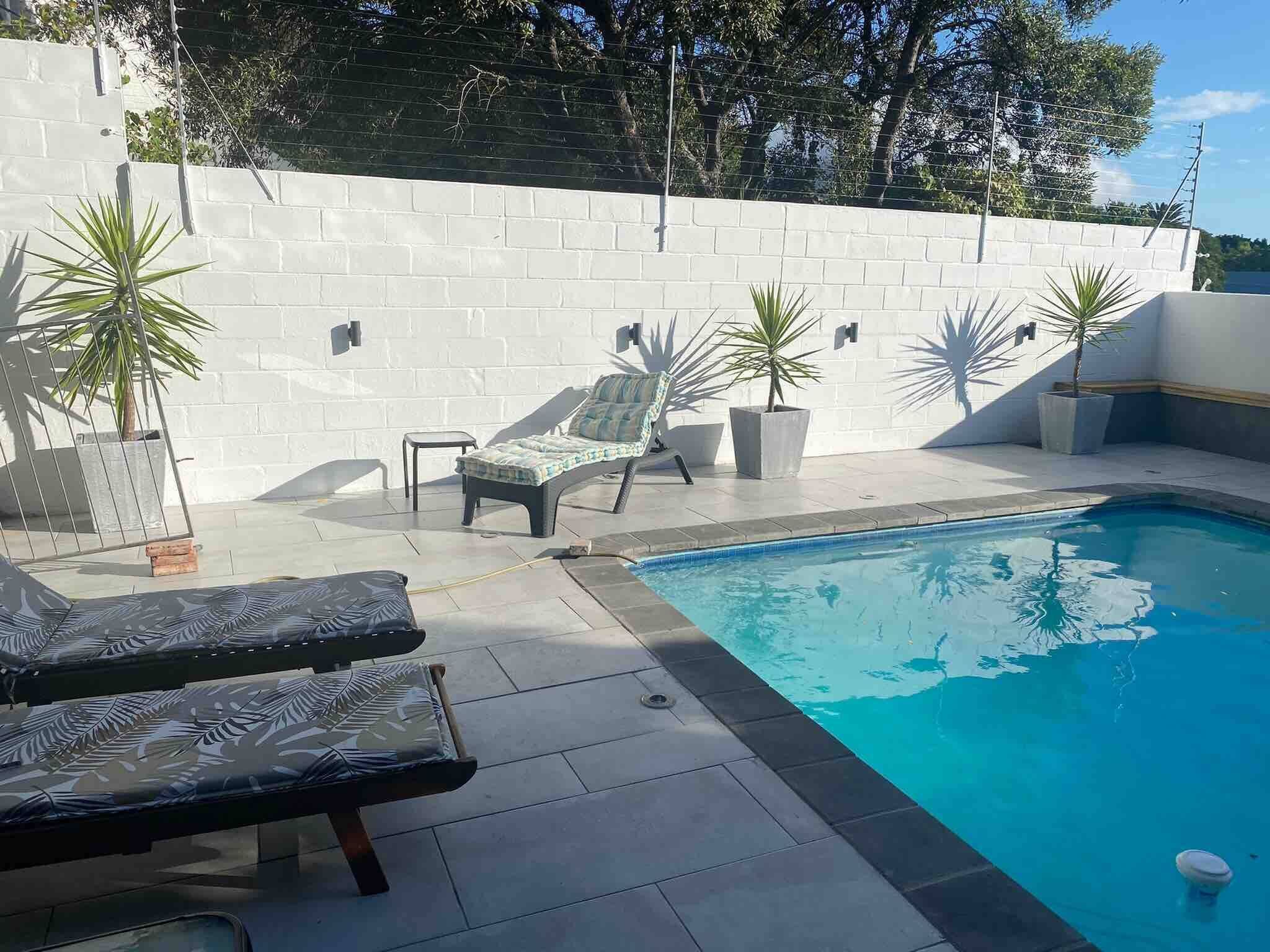 Ein Pool mit Liegestühlen und Pflanzen in Töpfen.