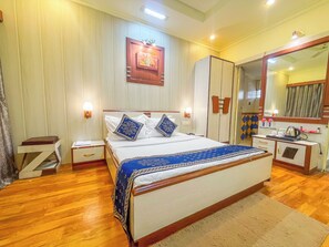 A hotel room with a bed, bedside tables, a wardrobe, a mirror, and a small desk with a kettle. - Hotel Thakur Galaxy - Nr Railway Station (Nagpur)
