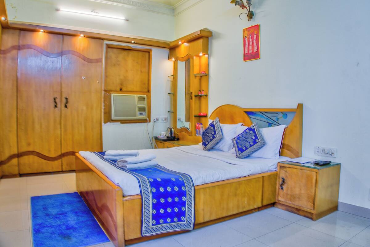 A bedroom with a wooden bed, a nightstand, a wardrobe, and a mirror.