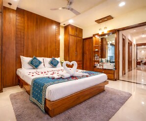 A hotel room with a large bed, wooden wardrobe, a ceiling fan, and a bathroom visible through an open door. - Hotel Thakur Galaxy - Nr Railway Station (Nagpur)