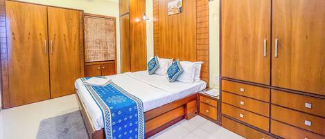 Une chambre à coucher comprenant un lit, une armoire en bois, un ventilateur de plafond et un appareil de climatisation.