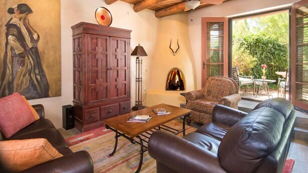 Una sala de estar con sofá, sillón, mueble de madera y un cuadro en la pared.