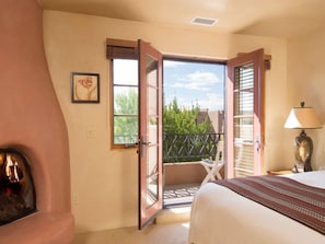 Una camera da letto con un letto, una sedia, una lampada, una porta aperta che dà su un balcone e un quadro appeso al muro.