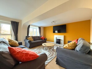 En moderne stue med to grå sofaer, et lille rundt sofabord og en pejs.