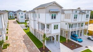 A residential complex with multiple two-story buildings, each featuring balconies and a central courtyard. - A Treasure To Sea 4 Bedroom Villa (Carolina Beach)