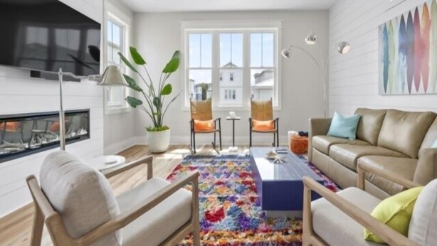 A modern living room with a sofa, chairs, a coffee table, a plant, and a colorful rug. - A Treasure To Sea 4 Bedroom Villa (Carolina Beach)