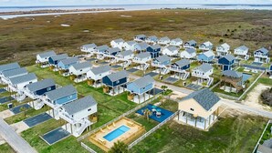 A coastal residential area with multiple two-story houses featuring attached decks and a swimming pool.