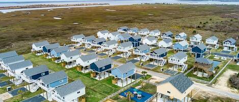 A coastal residential area with multiple two-story houses featuring attached decks and a swimming pool.