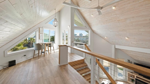 Un loft spacieux avec de hauts plafonds, des planchers en bois et de grandes fenêtres offrant une vue sur l’extérieur.