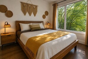 Ein Schlafzimmer mit einem großen Bett, Nachttischlampen, einem Fenster mit Blick auf Bäume und Wanddekoration.