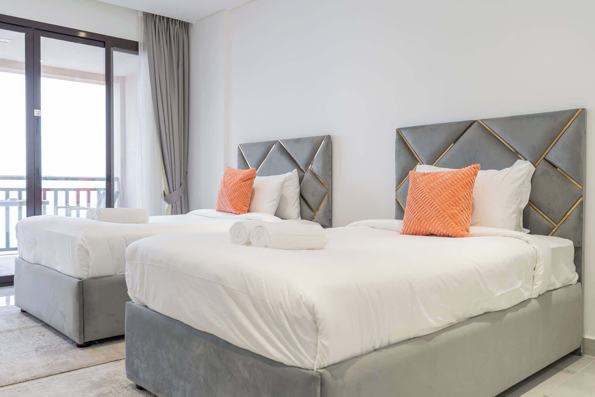 Une chambre d’hôtel avec deux lits, un balcon et vue sur la mer.