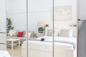 Ein modernes Hotelzimmer mit Bett, Sofa, kleinem Tisch und Spiegel.