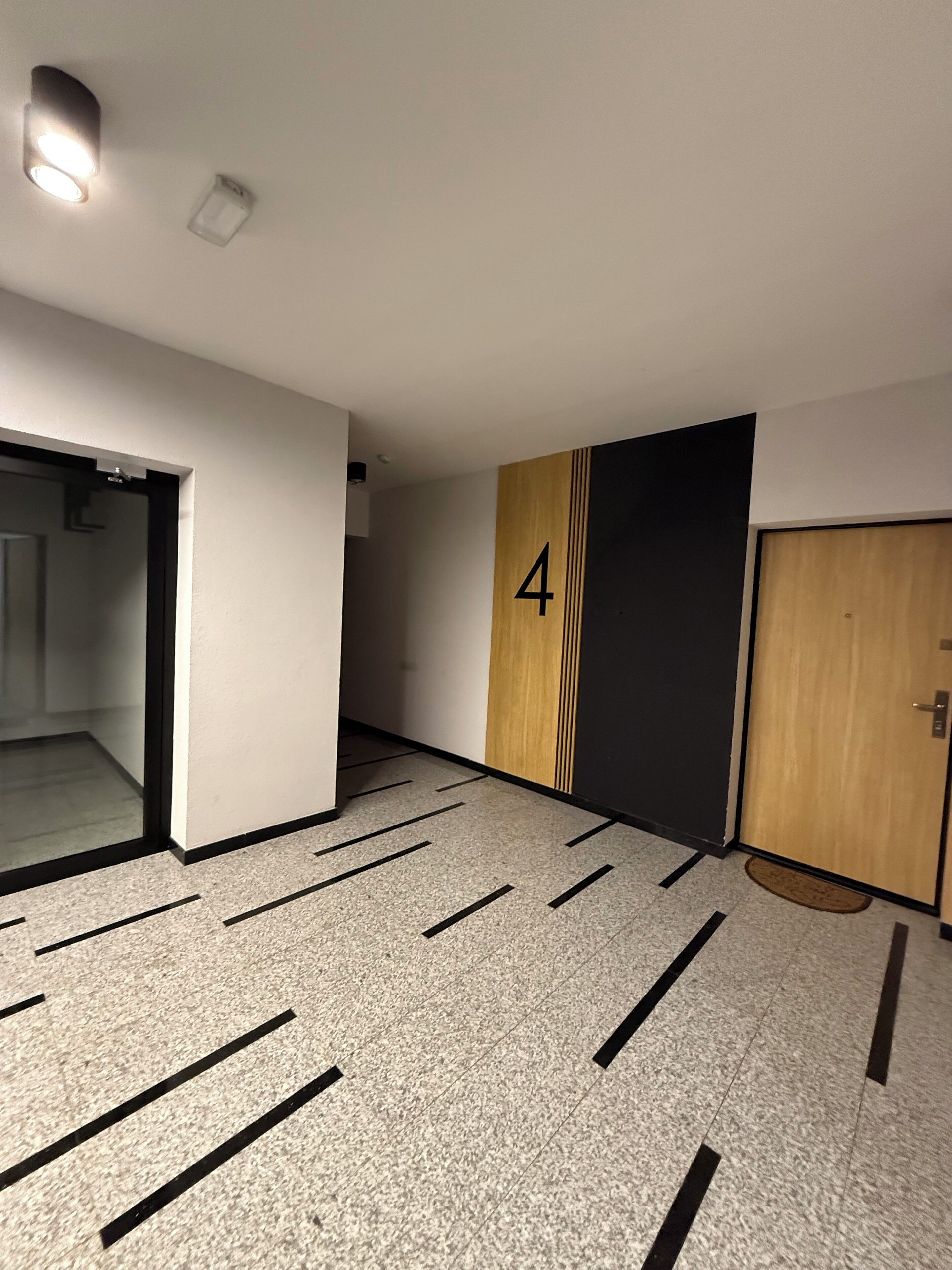 A hallway with a number 4 on the wall, a door, and a light fixture.