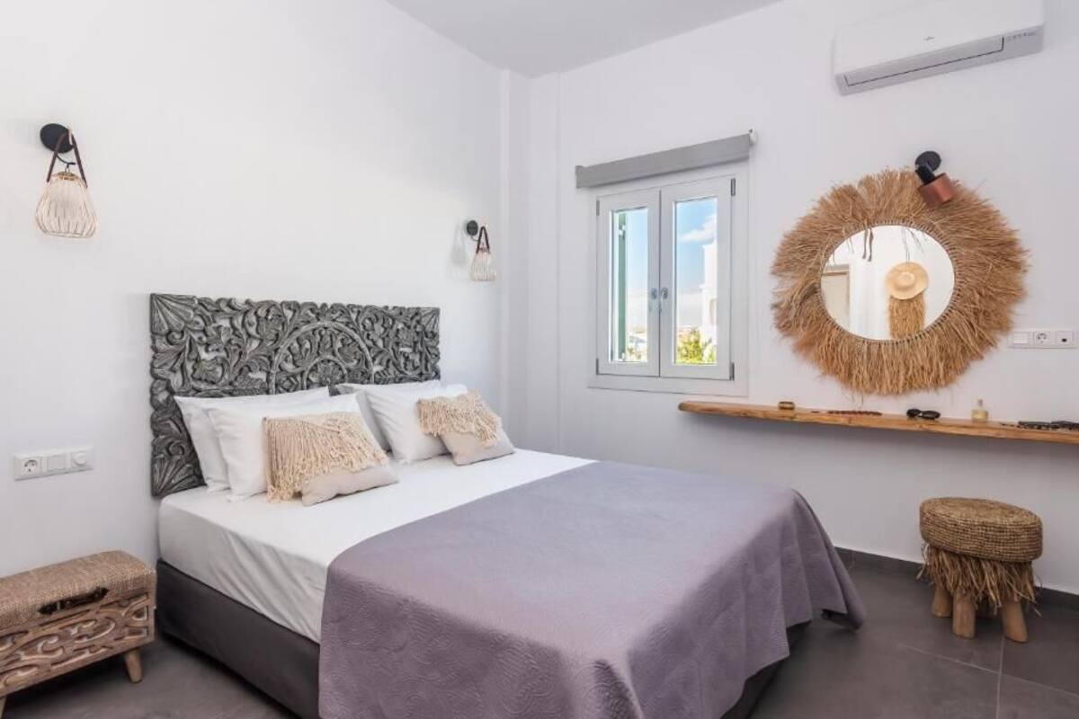 A bedroom with a bed, bedside tables, a mirror, and a window.