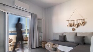 Ein modernes Wohnzimmer mit grauem Sofa, einem Couchtisch und Blick ins Freie durch eine Schiebetür.