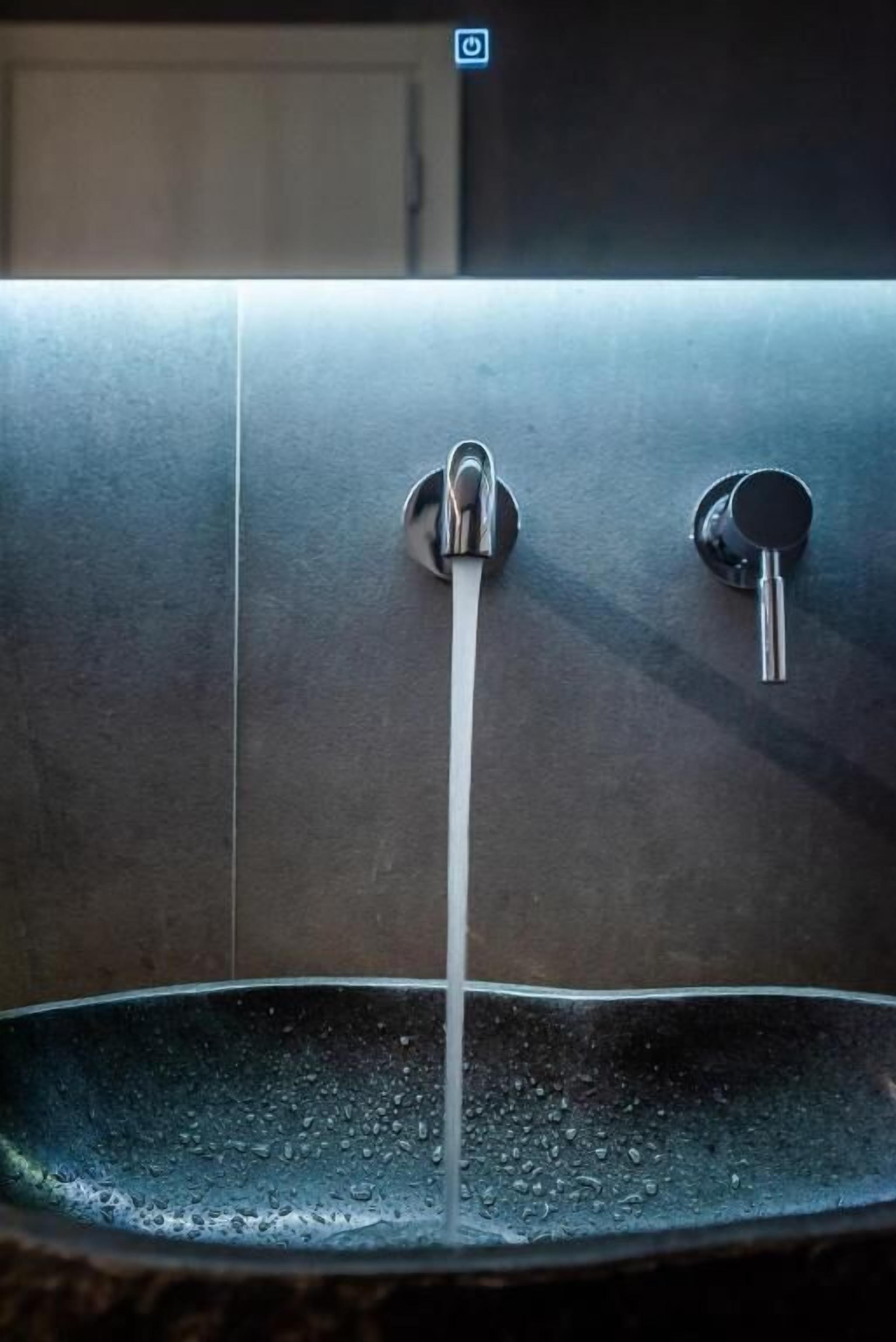 Un grifo metálico con agua corriendo hacia un recipiente.