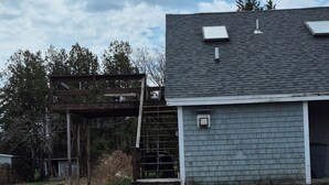 Un bâtiment doté d’un toit gris et de panneaux solaires, entouré d’une zone de terre battue où la végétation est clairsemée.