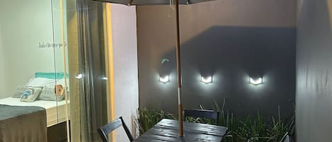 A patio with a table and chairs, an umbrella, and a bed with a view.