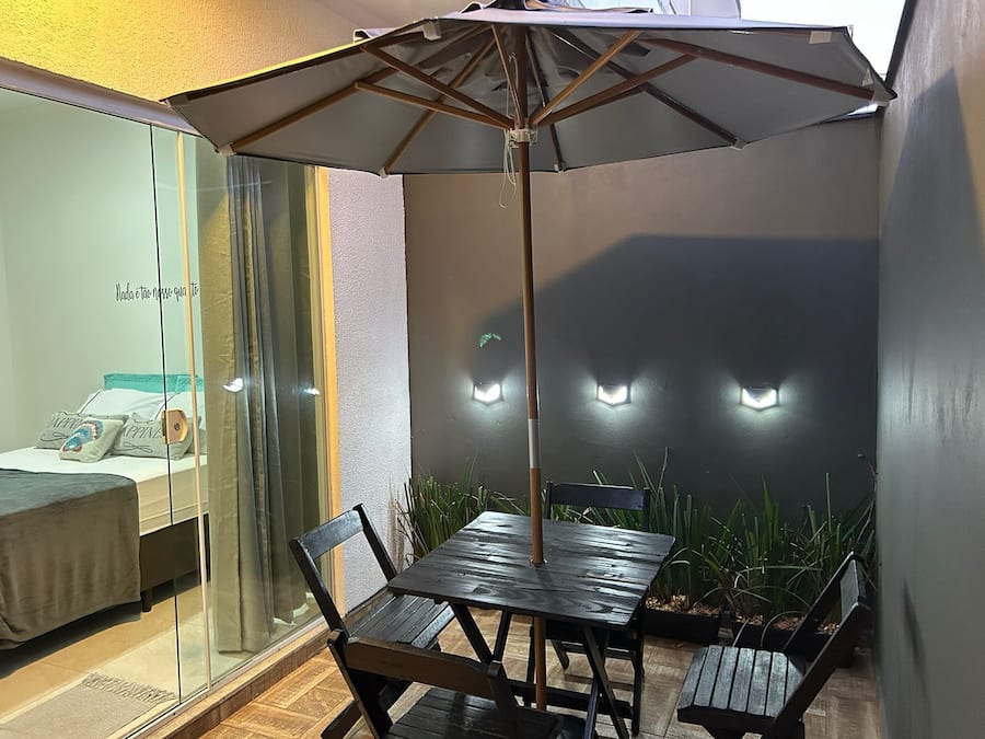 Un patio con mesa y sillas, una sombrilla y una cama con vistas.