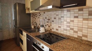 Una cocina con encimera de granito, electrodomésticos de acero inoxidable y salpicadero de azulejos.