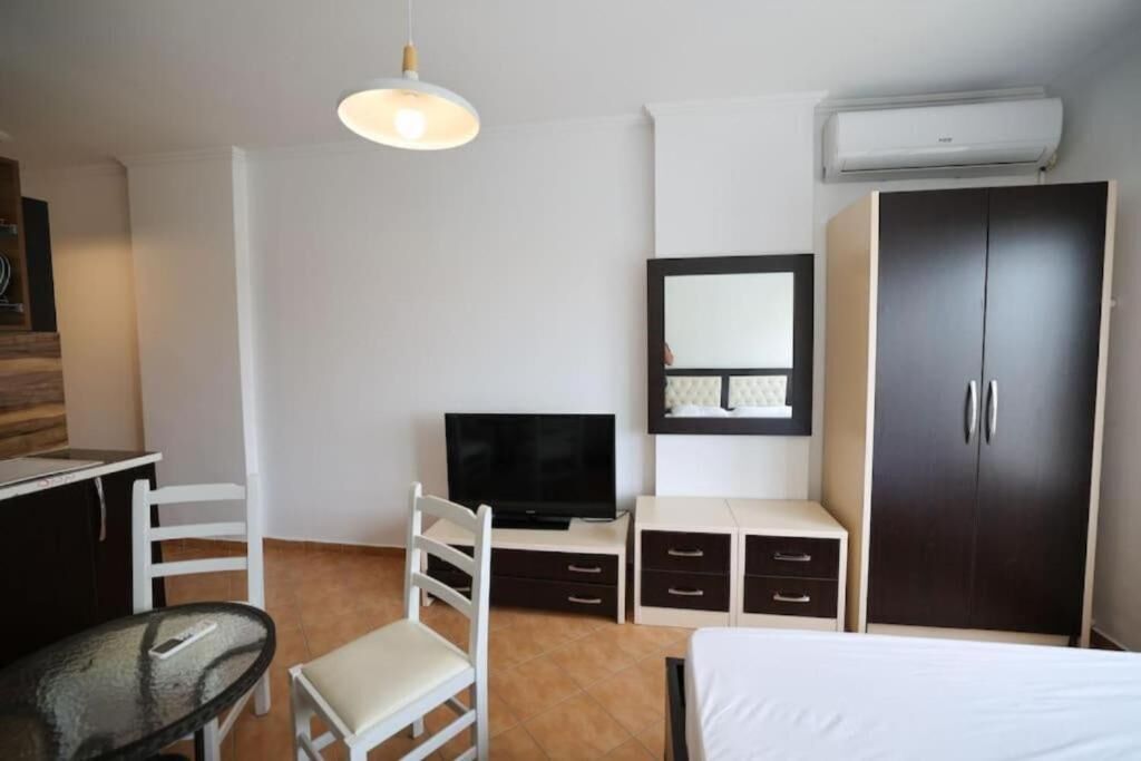 A hotel room with a bed, a TV, a desk with a chair, a wardrobe, and a hanging light fixture.