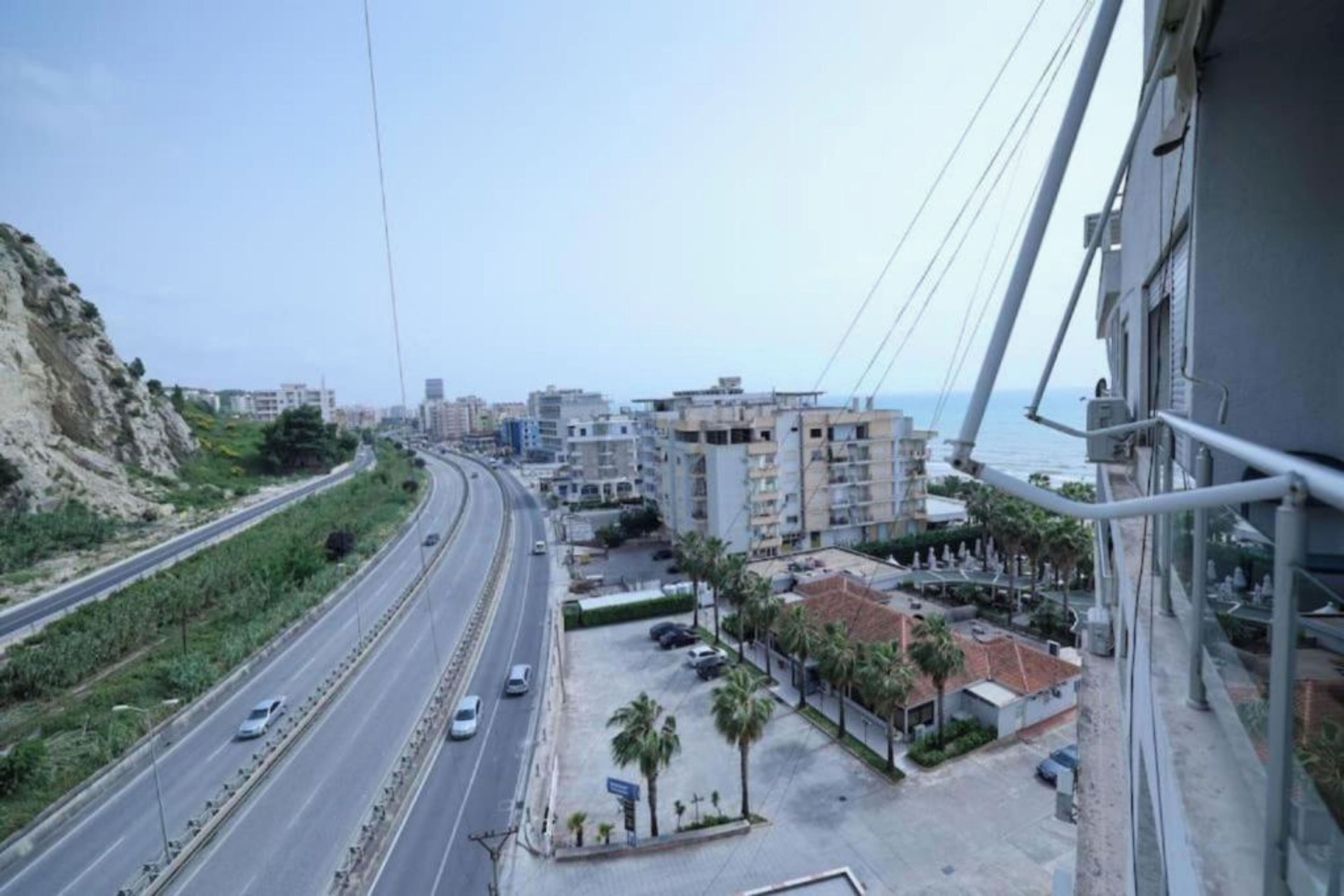 Un paysage urbain côtier avec une autoroute, des bâtiments et une vue sur la mer.