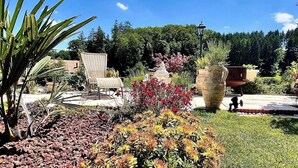 A garden with a patio area, chairs, and a large planter. - Guest Room, Enjoy the peaceful Bernese Seeland (Grossaffoltern)