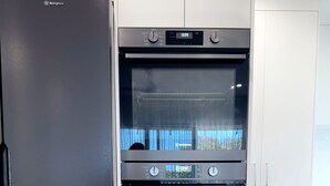 Une cuisine avec un réfrigérateur noir, un four à deux cavités et des armoires blanches.