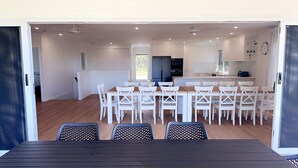 Une cuisine moderne avec des meubles blancs, un îlot central et un coin repas avec des chaises blanches.