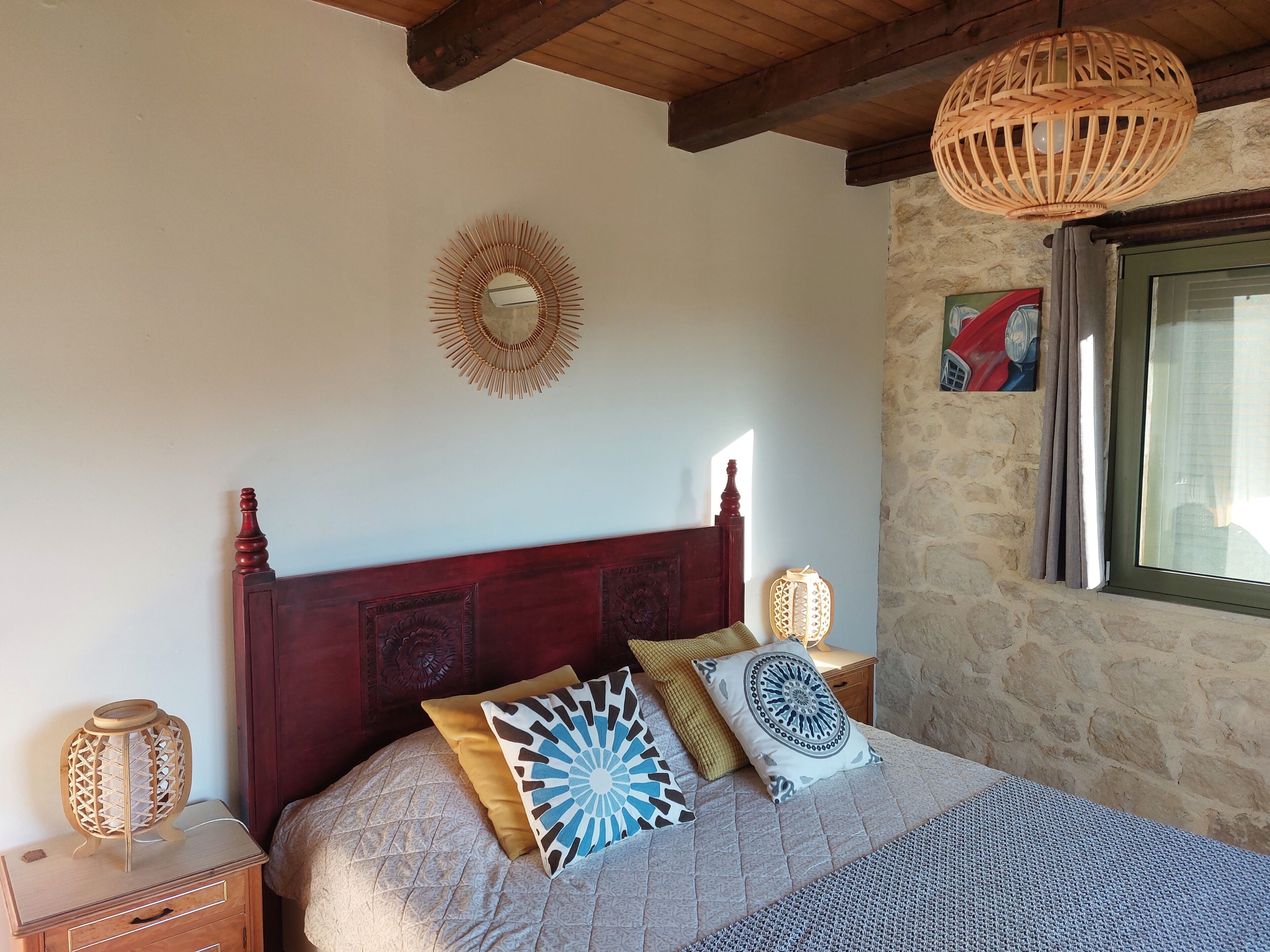 Une chambre à coucher avec une tête de lit en bois, un miroir décoratif et un lit recouvert d’une literie à motifs.