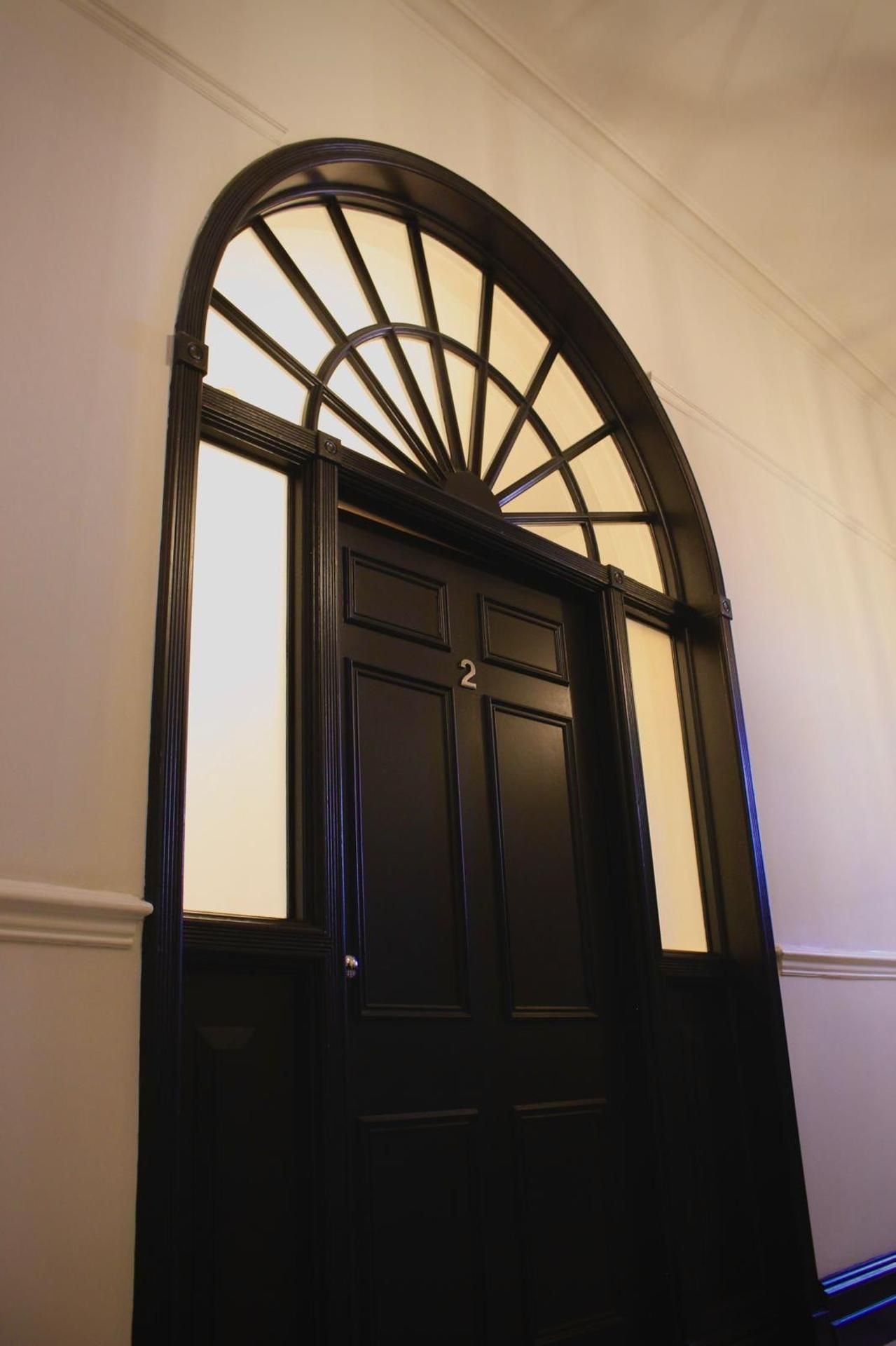 A black door with a semi-circular window above it.