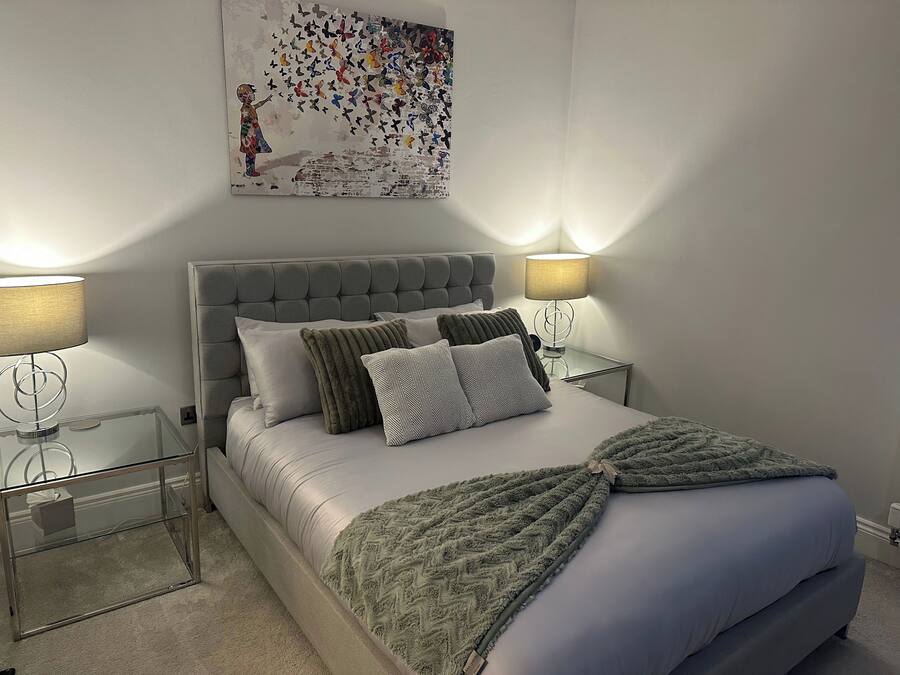 Un dormitorio con una cama, dos mesitas de noche, una lámpara de pared y un adorno en la pared.