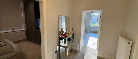 A hallway with a bed, a mirror, and a radiator.