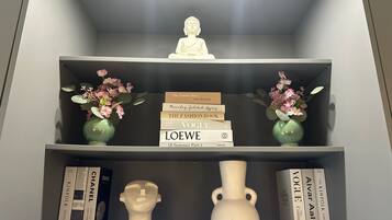 A bookshelf with books, a Buddha statue, and decorative vases.