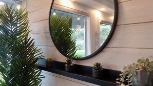 A bathroom with a large mirror, wooden walls, and potted plants. - Seascape Oasis - 2BDRM - Ocean View - Kitchen (Nanoose Bay)