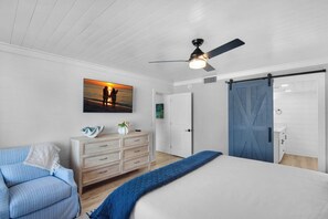 A bedroom with a bed, a dresser, a blue sofa, a painting, a ceiling fan, and a sliding barn-style door. - ☀️Steps to Beach | Gulf Views |2 Pools + Kiddie Pool | 2BR | Mainsail 441☀️ (Miramar Beach)