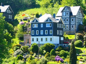 Un edificio a più piani con uno stile architettonico tradizionale, immerso nel verde e circondato da alberi.