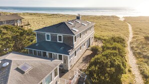 Una casa de dos plantas con techo plano, ventanas grandes y vista a la playa.