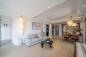 A modern living room with a sofa, coffee table, and dining area with chairs.
