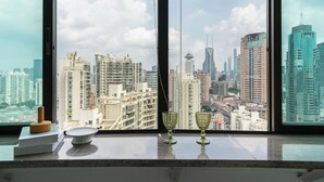 A view from a high-rise window overlooking a cityscape with modern buildings and a clear sky. - YIDU (Nanjing West Road Store) (Shanghai)