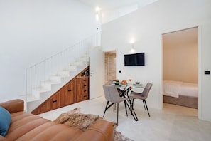 Stylish living area with a staircase, dining space, and a comfortable bed.
