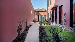 Un sendero estrecho que conduce a un edificio con ventanas grandes y una pared exterior roja.