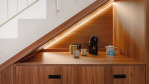 Una repisa de madera con una cafetera, un hervidor y dos tazas.