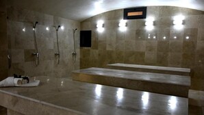 Un baño moderno con encimera de mármol, múltiples cabezales de ducha y un banco integrado.