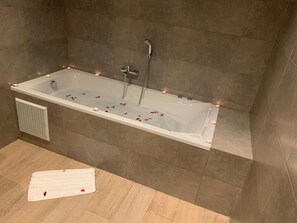 Een moderne badkamer met een vrijstaand bad, douchekop en handdoekhouder.