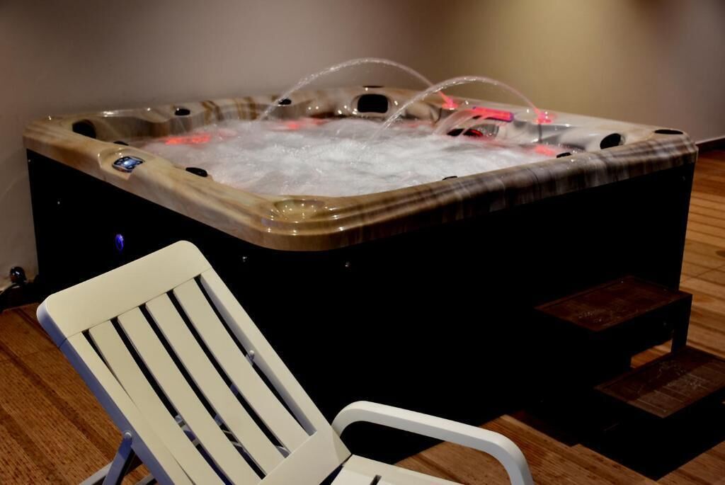 A hot tub with a wooden exterior and a white chair in front.