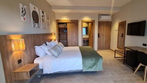 Un dormitorio moderno con cama, mesitas de noche, un escritorio y un televisor.